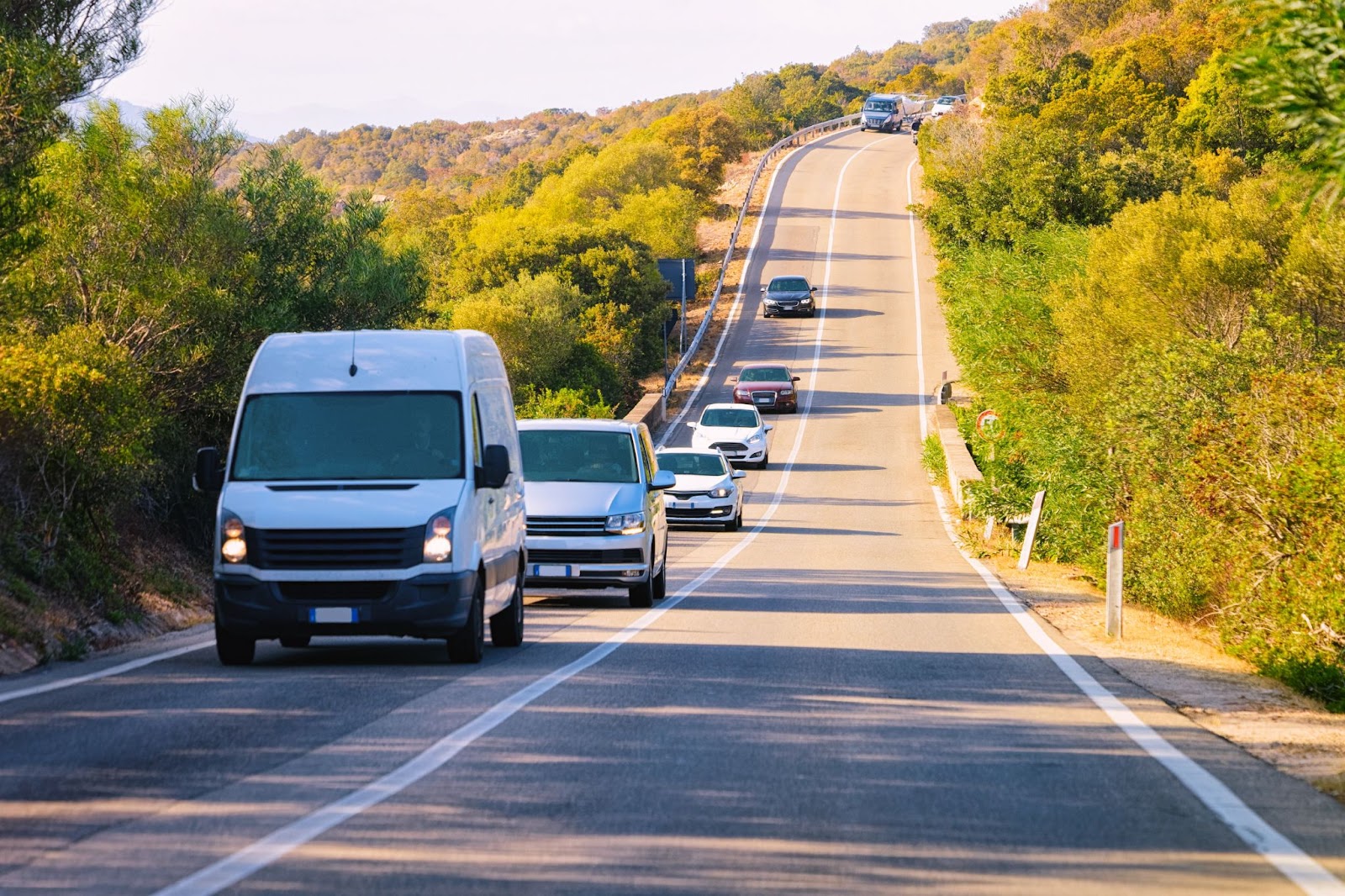 White van leading a convoy on a country road