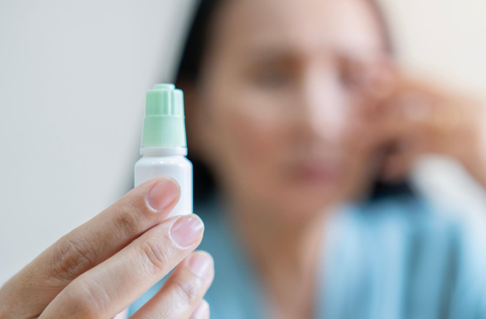 A close up of a bottle of eye drops which may be expired due to discoloration.