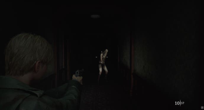 Cuplikan layar dari Silent Hill 2 Remake: Gambarnya hampir sepenuhnya gelap kecuali bentuk humanoid di bagian tengah. James mengacungkan senjatanya, garis bidiknya diarahkan ke makhluk itu.