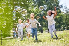 group of little children with toothy smiles on their faces enjoying warm sunny day while participating in soap bubbles show