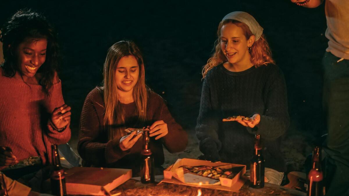 People wearing casual outfits on a beach bonfire
