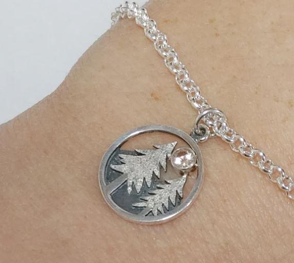 A silver bracelet with a silver pendant on it

Description automatically generated