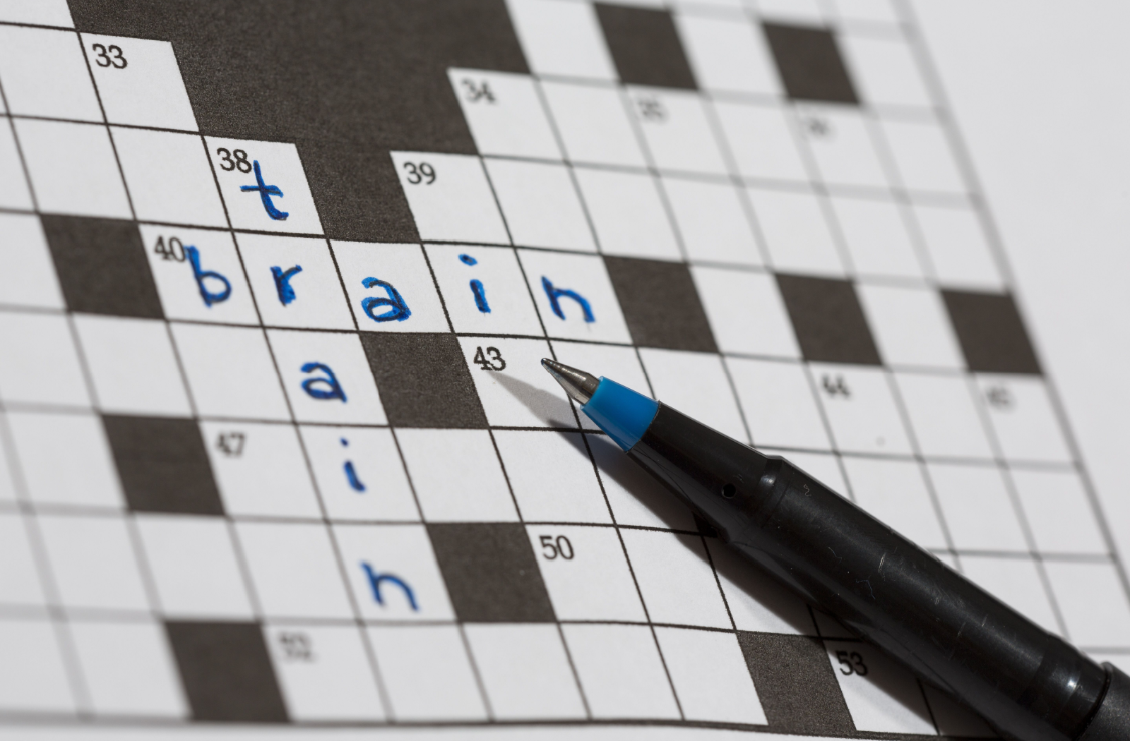 A paper crossword reads 'brain' across and 'train' down, the words intersecting 'r'.