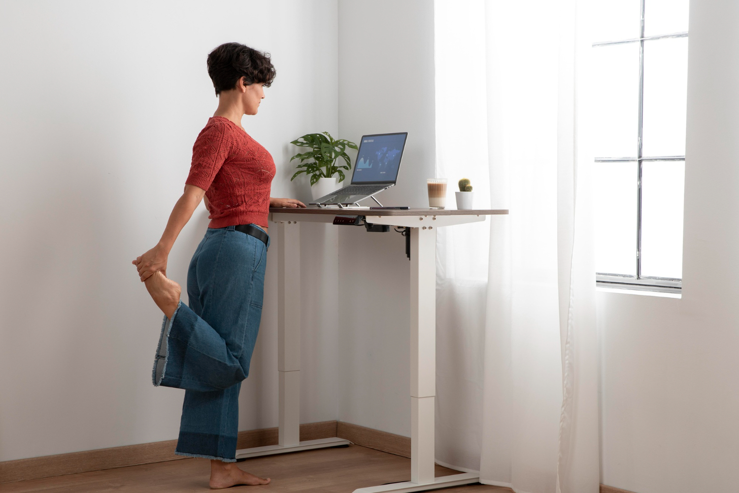 Woman standing and working at an adjustable standing desk.