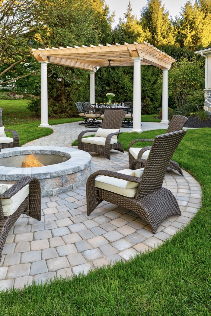 A landscape designer creates an outdoor oasis, complete with a fire pit and pergola.