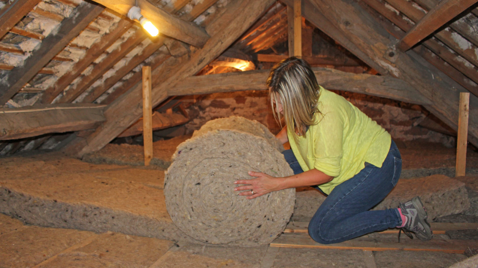 DIY woman installing thermafleece loft insulation | Shush! A Guide to Acoustic Insulation | Insulation Merchant