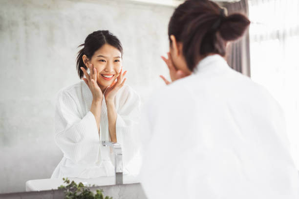 Confident woman admiring her smooth, glowing skin in the mirror after consistent use of beauty supplements.