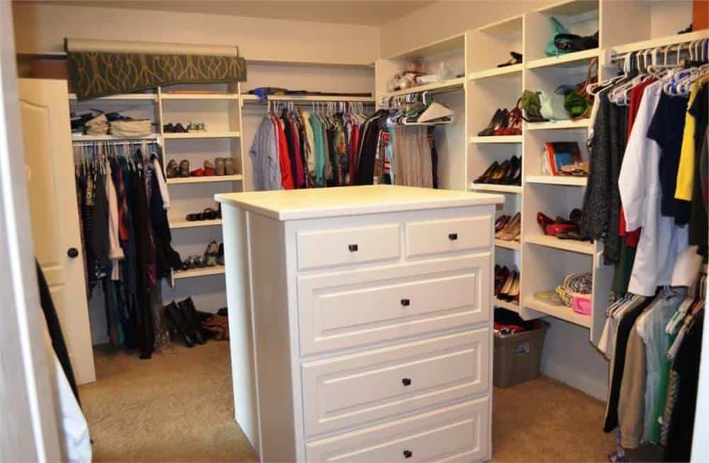 The primary walk-in closet is filled with built-in shelves, pole racks, and a center island with white drawers.The primary walk-in closet is filled with built-in shelves, pole racks, and a center island with white drawers.