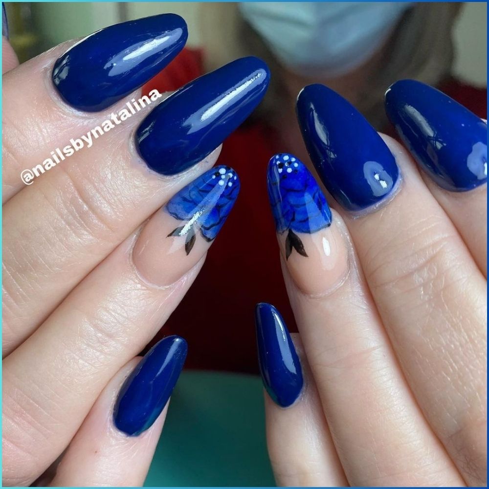 Close up of hands with flowered designed blue nails having black and blue lined rose flower on ring finger