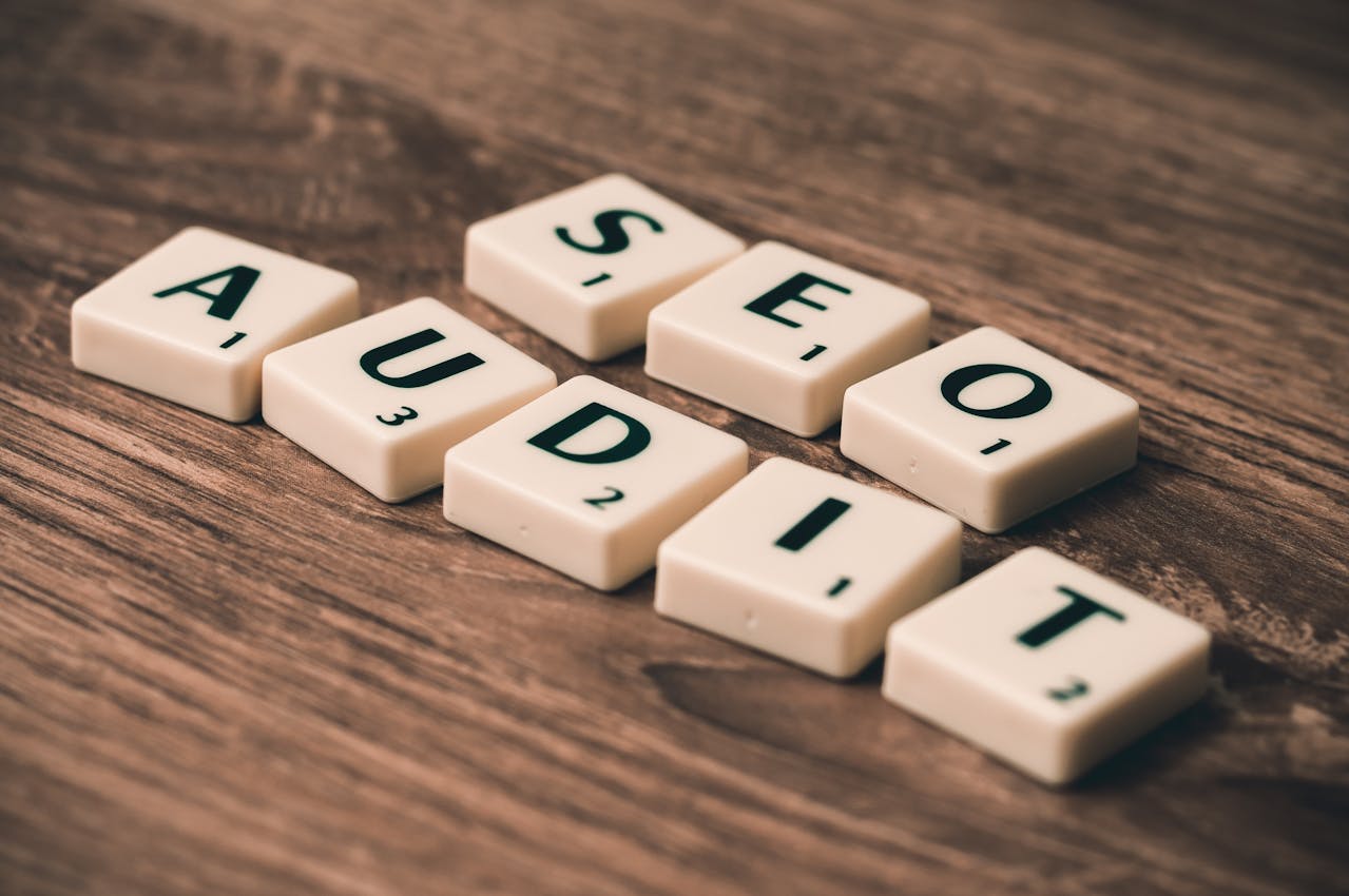 Scrabble tiles arranged to spell 'SEO AUDIT' on a wooden surface, representing the concept of analyzing and improving search engine optimization.