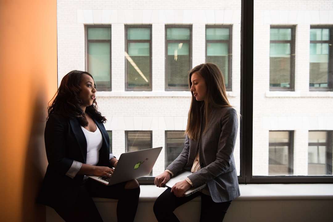 Two professionals reviewing and discussing the integration capabilities of multi-channel marketing software on a laptop