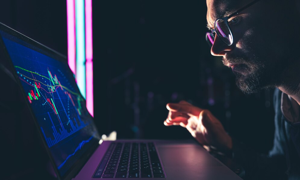Man analyzing a market chart on a laptop.
