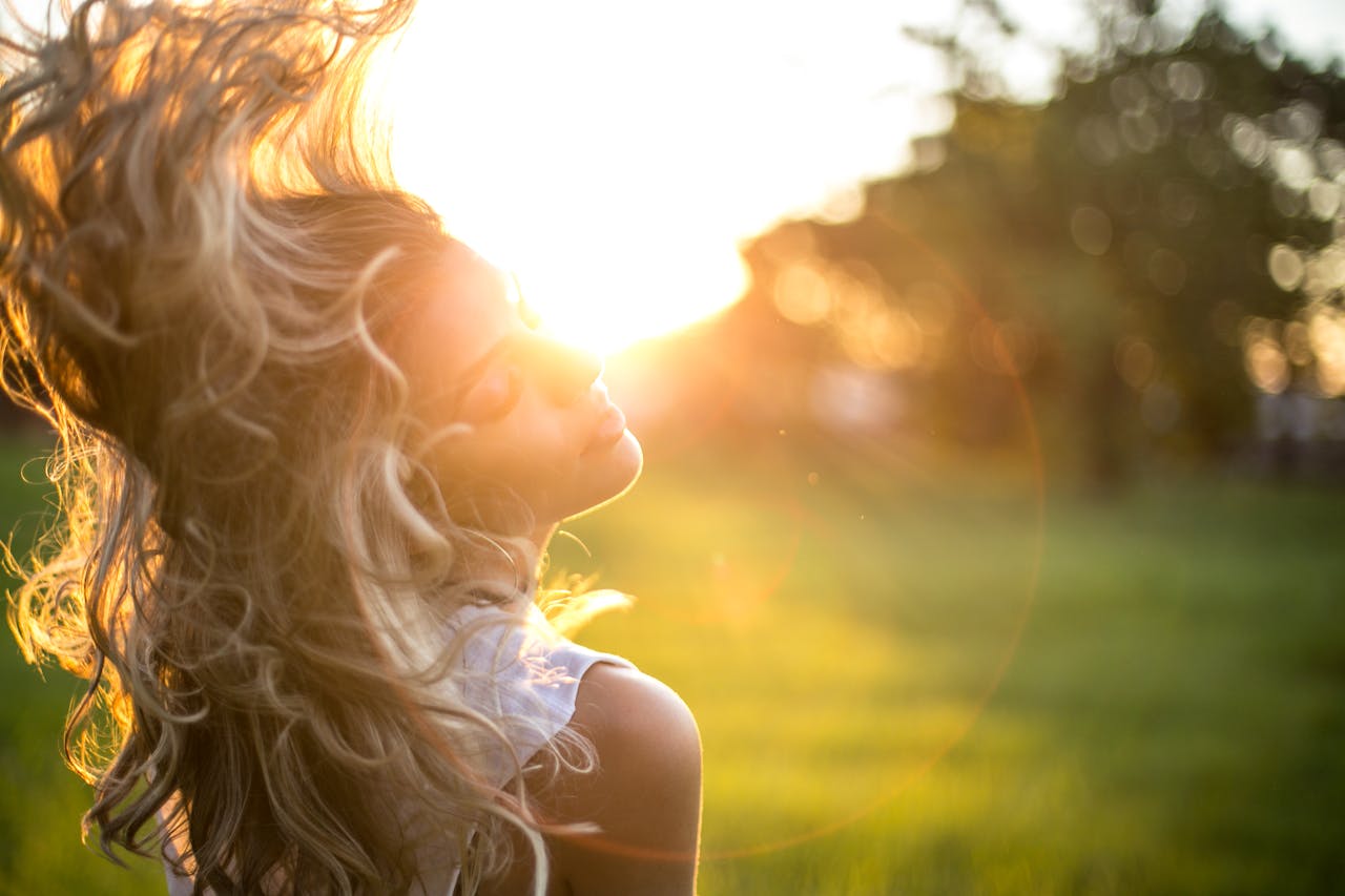 A woman with flowing hair in the wind, showcasing the beauty of natural herbal hair care over chemical dyes.