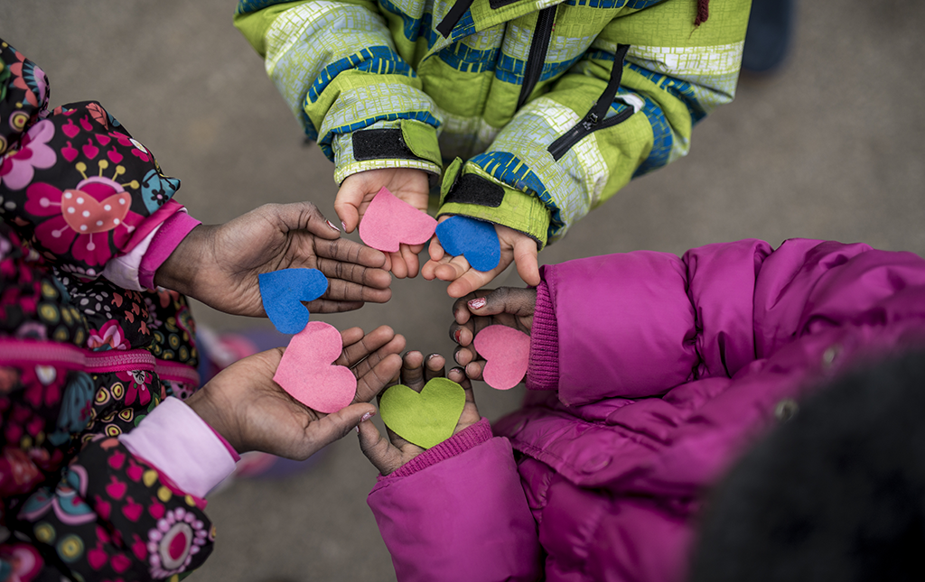 Children at school holding paper hearts during a Week of Kindness event.