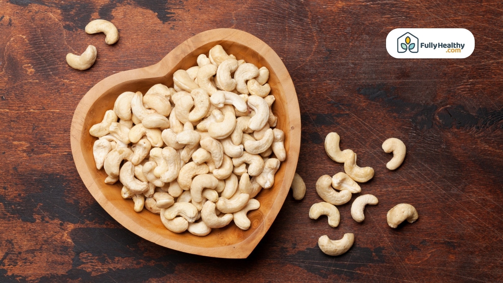 Cashews in a heart shaped bowl on wooden table surface