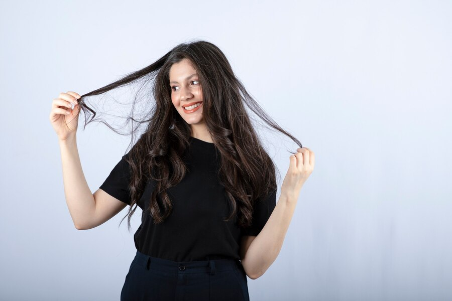 Brunette girl in black top playing with hair