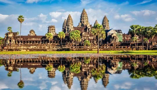 Angkor Wat with trees and water in front of itDescription automatically generated