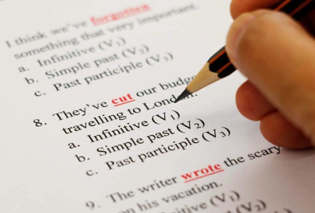 A hand holding a pencil over an 11 Plus Exam