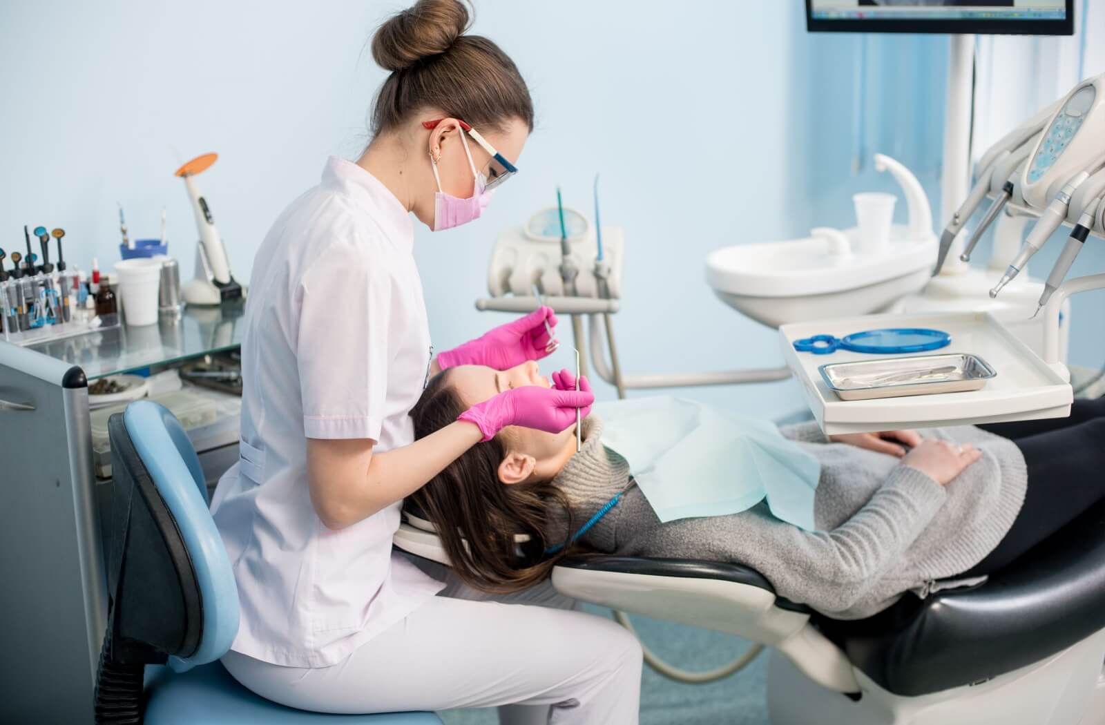 A dental hygienist performs a routine dental cleaning, removing plaque and tartar buildup from their patient's teeth.