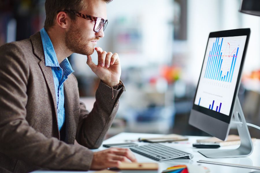 Man analyzing data on a computer screen in an office.