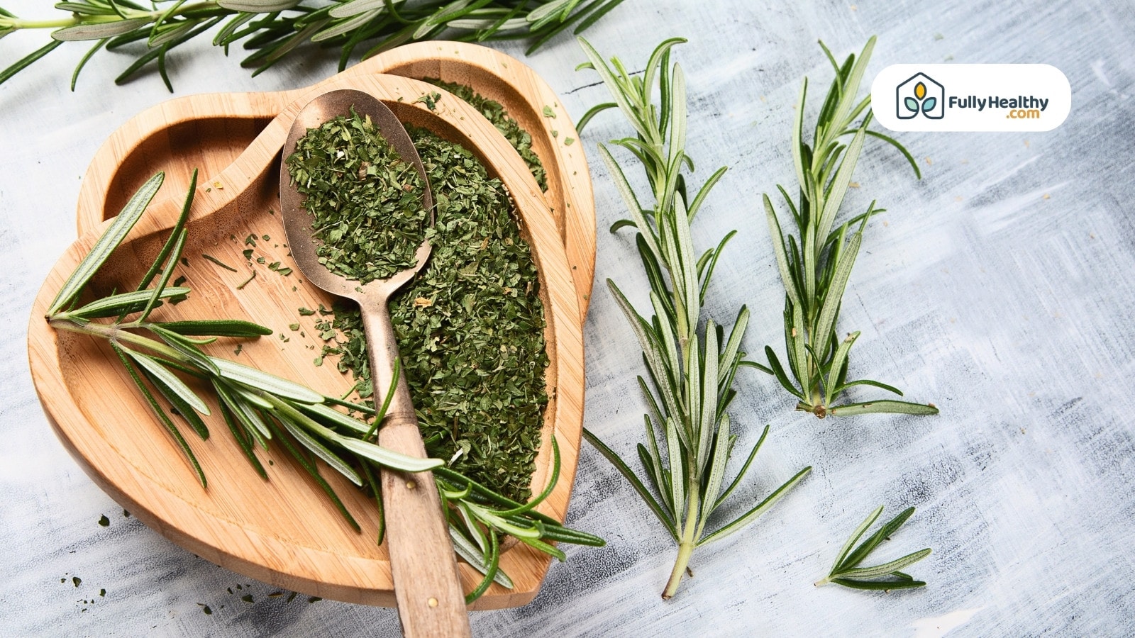 Dried rosemary flakes with fresh sprigs on wooden heart dish