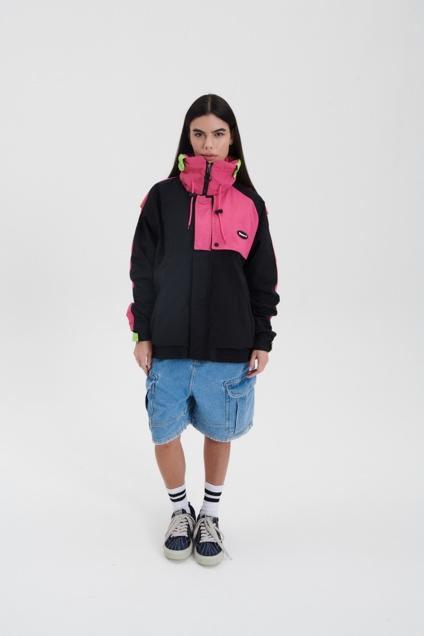 Mulher em pé posando para foto com blusa verde e rosa