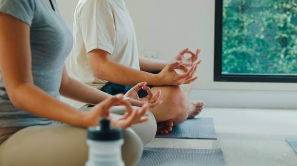 Two people meditating indoors, finding peace and balance through mindfulness and stress management.