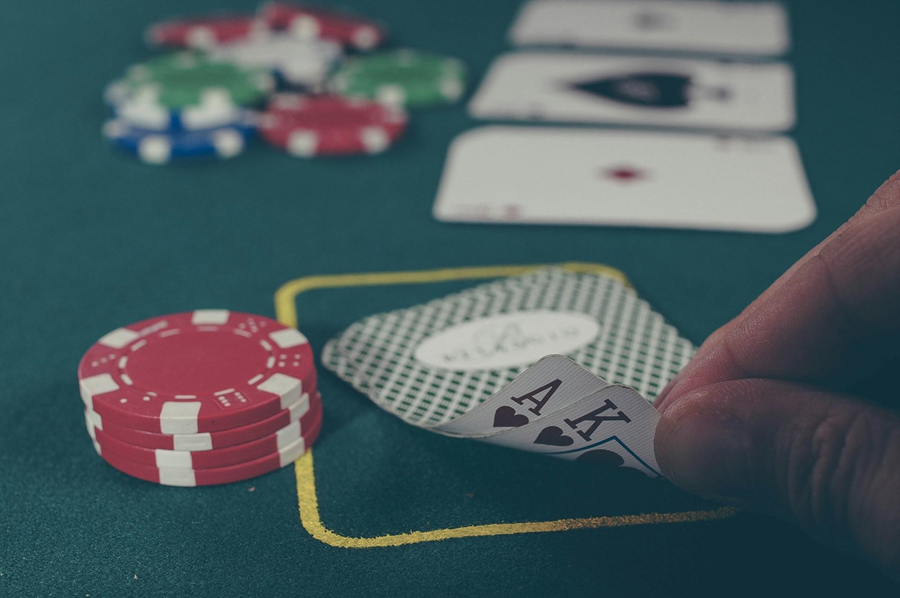 A person holding black ace and king spades on a poker table