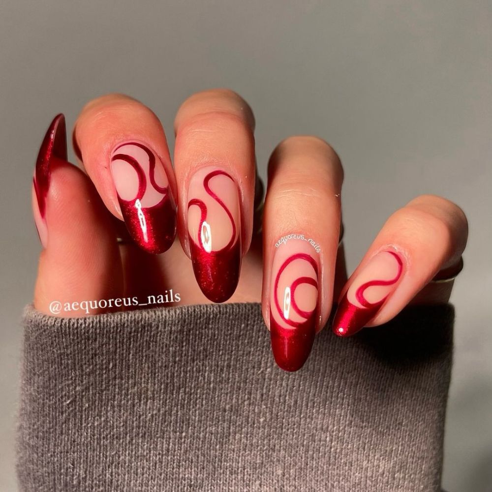 Close up of hands having Christmas red nails with Swirly Red Almond Nails