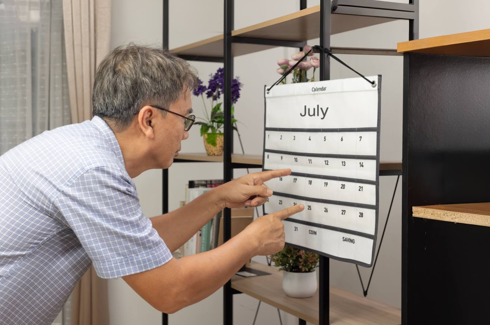 A senior looking and pointing at a calendar  with both index fingers in confusion.