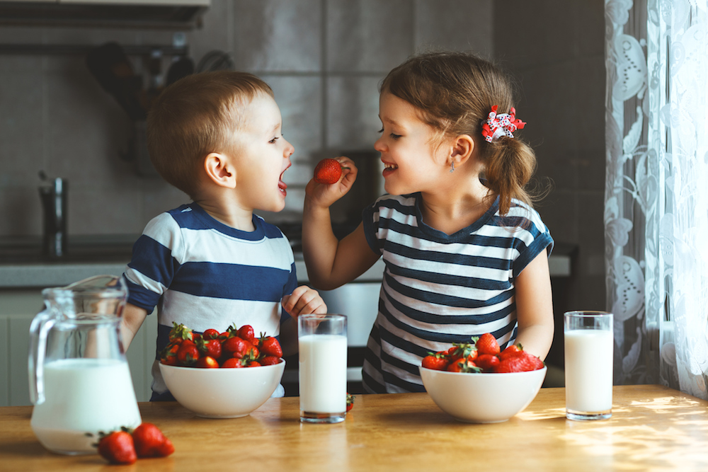 Two siblings happily sharing a healthy meal.
