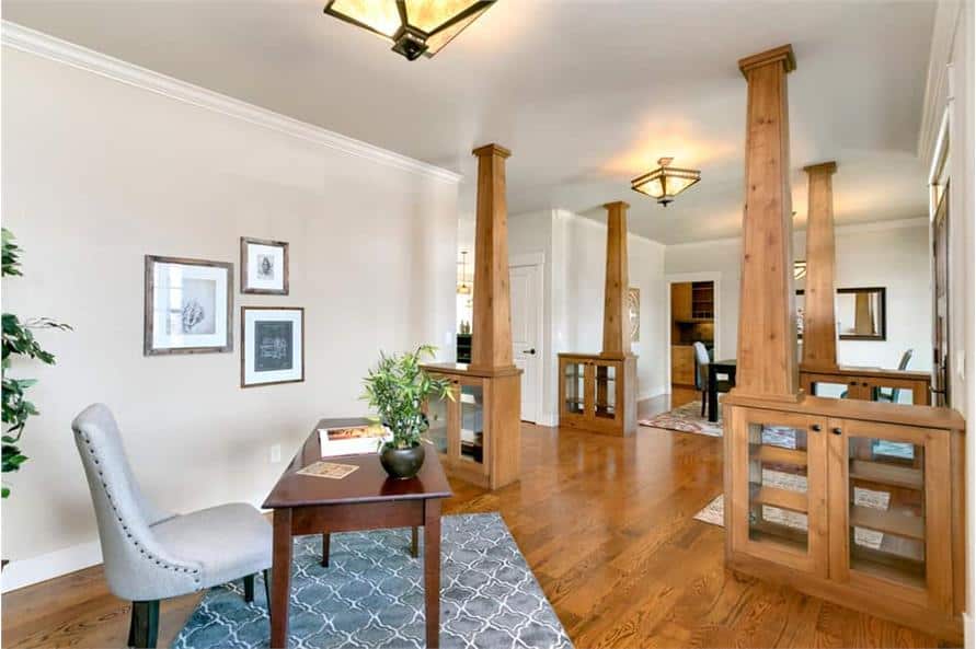 The home office offers glass front cabinets, a wooden desk, an upholstered chair, and a patterned area rug.