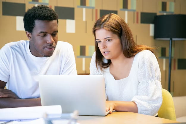 Two people discussing good feature article topics on a laptop