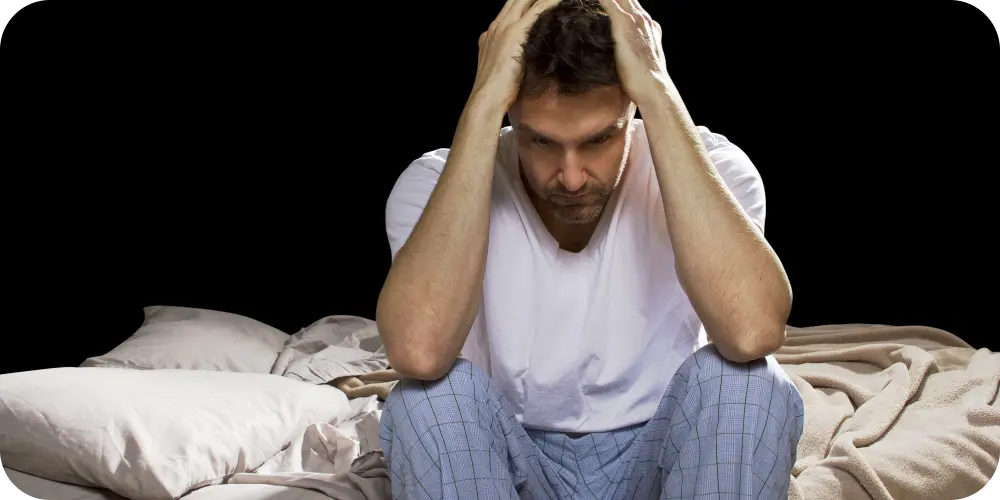 man sitting on bed frustrated