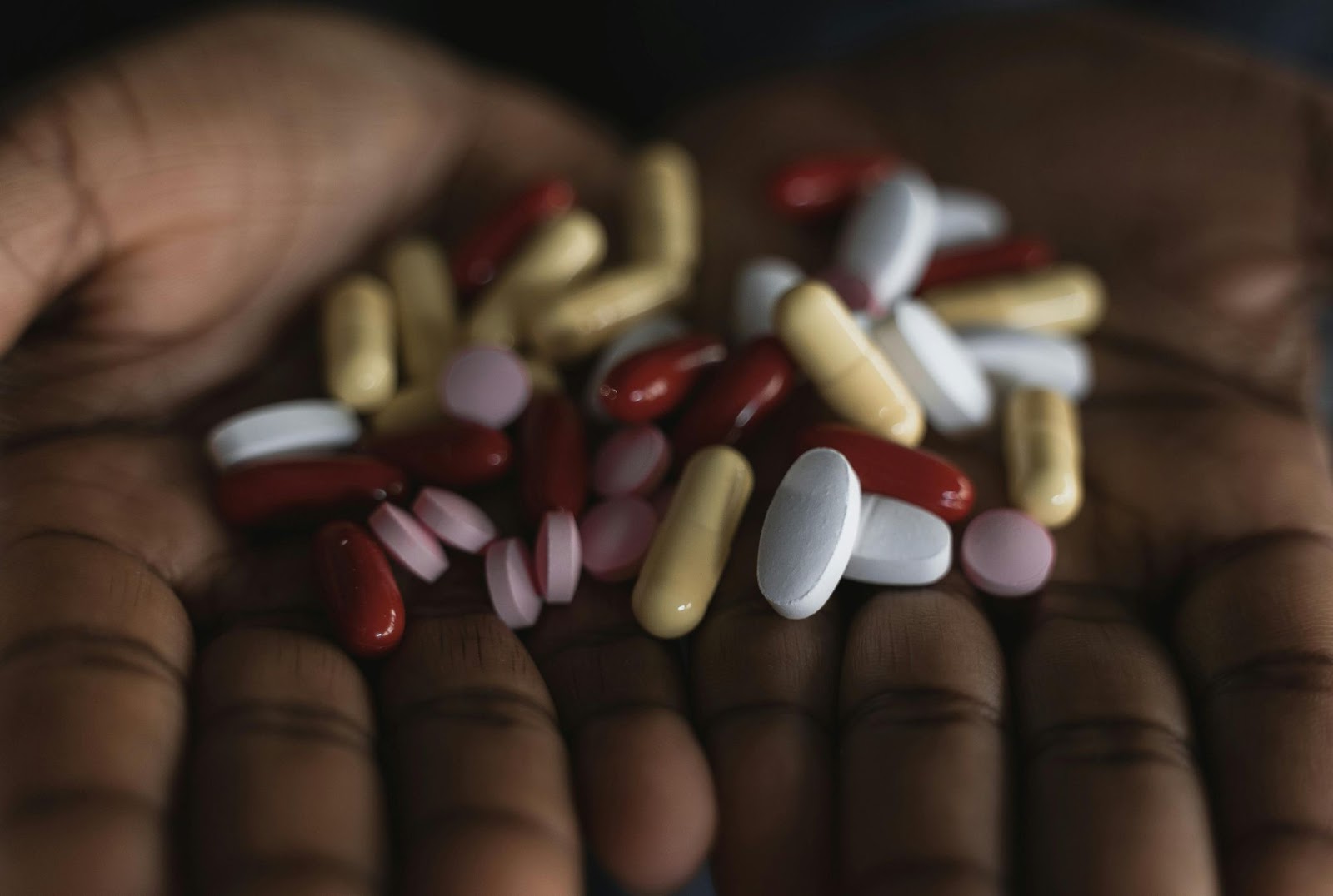 Close-up of hands holding a variety of colorful pills