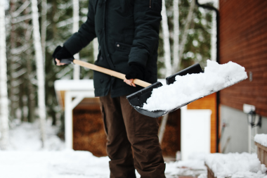 essential winterizing tips for your michigan home homeowner shoveling snow with plastic shovel on patio custom built okemos