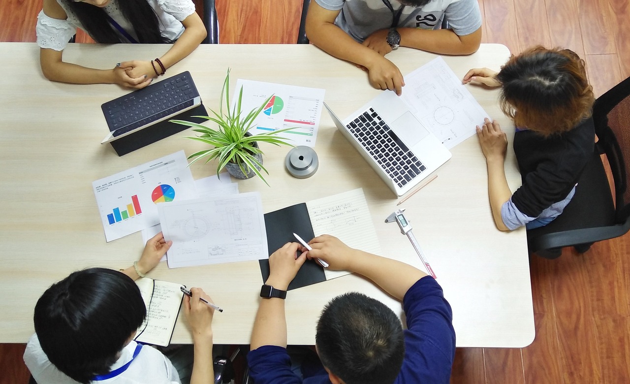 Pessoas ao redor de uma mesa de trabalho analisando dados