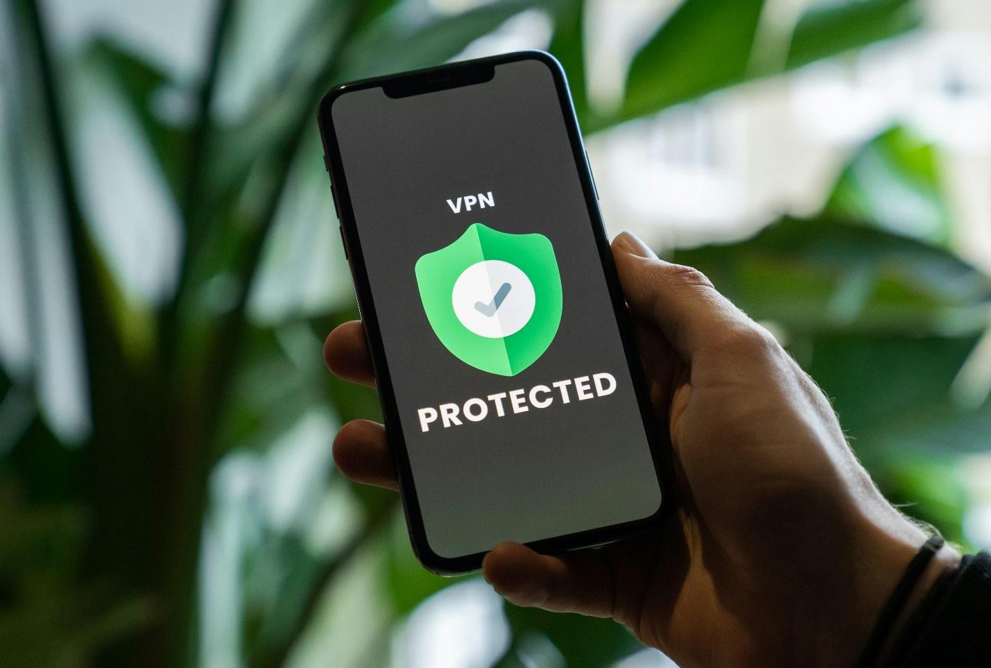 person holding black phone with the screen showing VPN protected