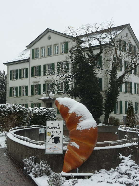 A large croissant in front of a building

Description automatically generated