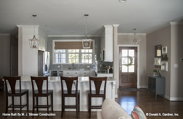 The kitchen features a breakfast bar lined with wooden counter chairs.