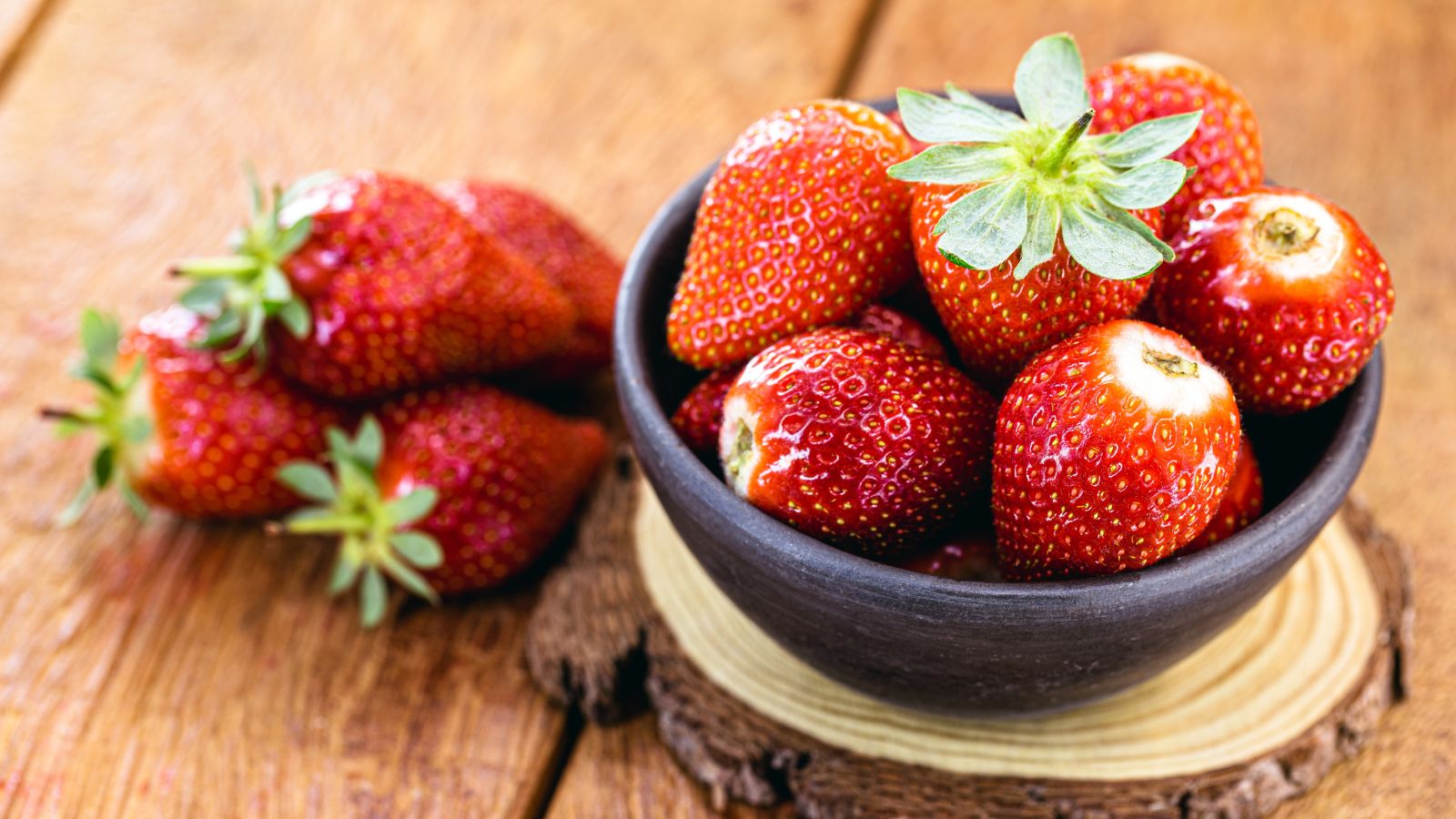 A shot of several freshly harvested fruits placed in a bowl in a well lit area indoors