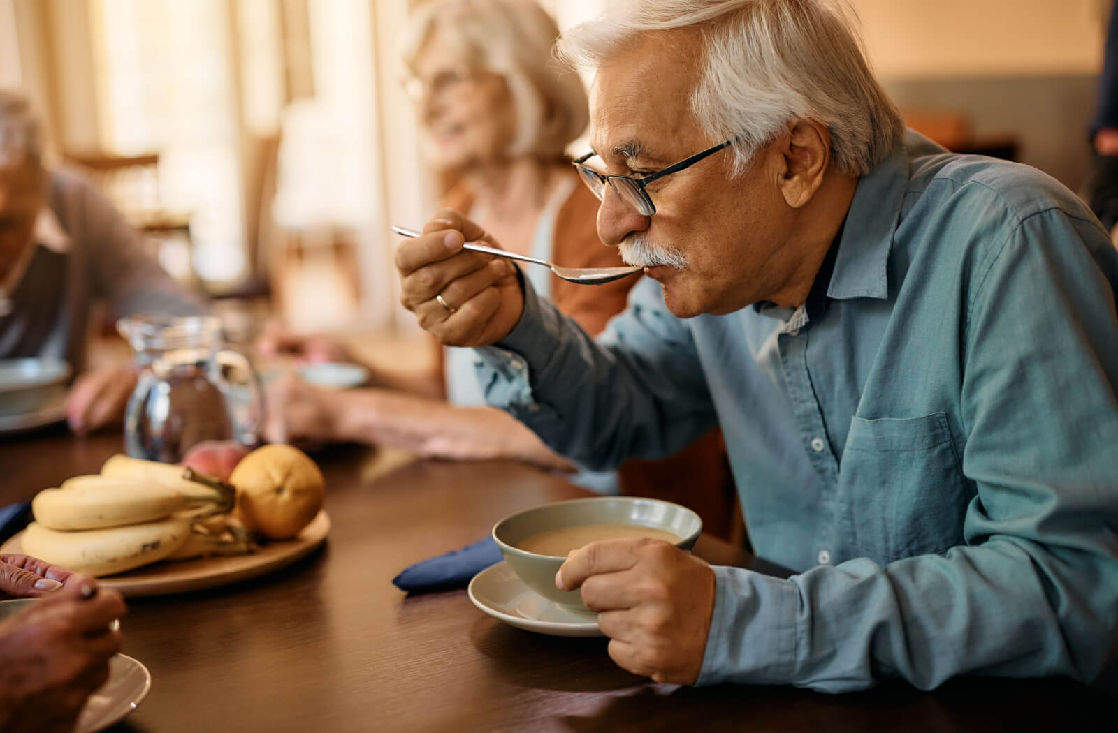 An older adult in memory care eating soup during a nutritious meal.