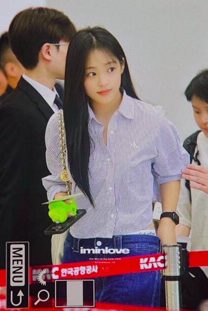 This contains an image of Minji on a crisp pinstripe shirt with well-fitted jeans