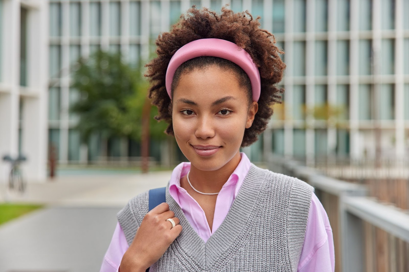 Uma mulher de cabelos cacheados posa para a foto com uma tiara rosa.