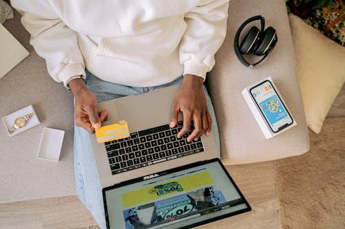 Free Person shopping online with a credit card on a laptop, emphasizing convenience and technology. Stock Photo