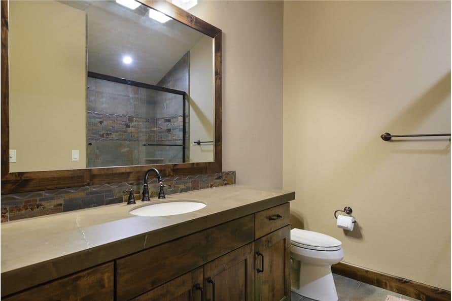 This bathroom offers a toilet, a sink vanity, and a walk-in shower reflected in the large framed mirror.