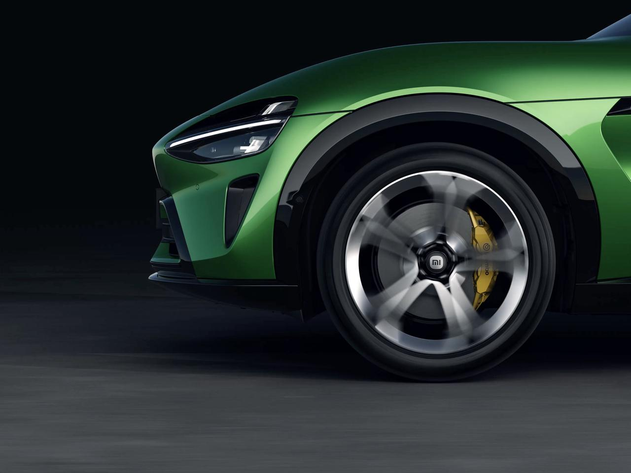 Close-up of the front wheel hub and brake system of a green sports car, with a dark background.