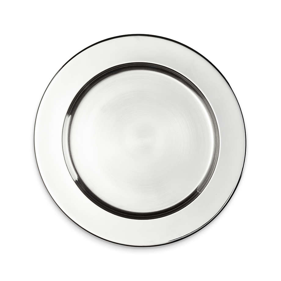A polished stainless steel charger plate from Crate & Barrel, elegantly placed on a dining table, showcasing its sleek, reflective surface and modern design.