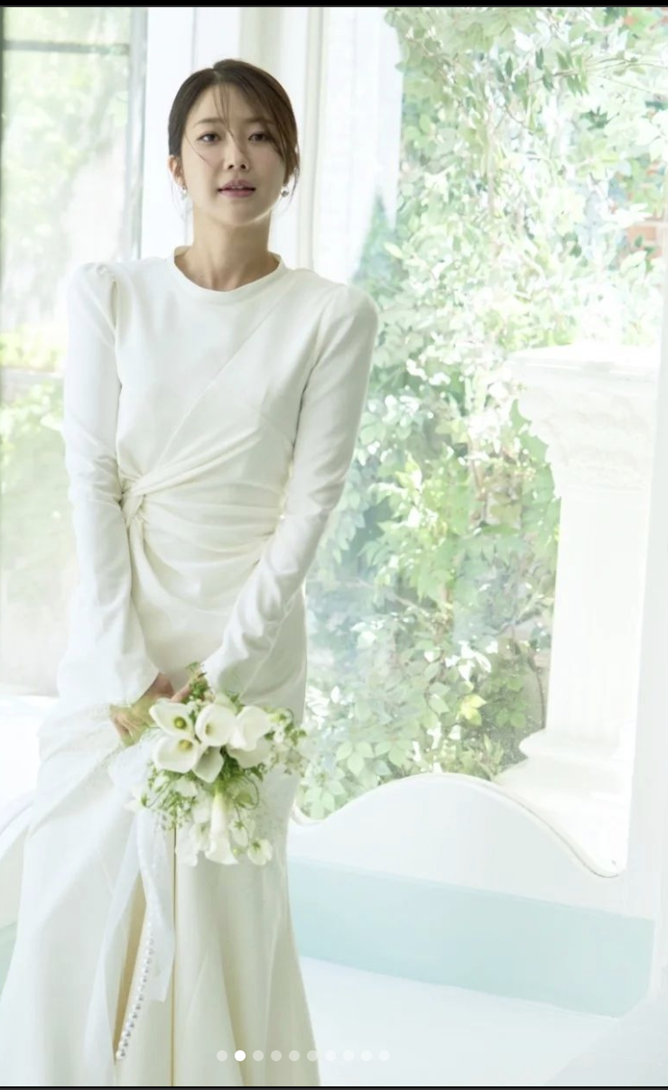 A photo of Seo Hae Won wearing a white gown with her flower in her hand 