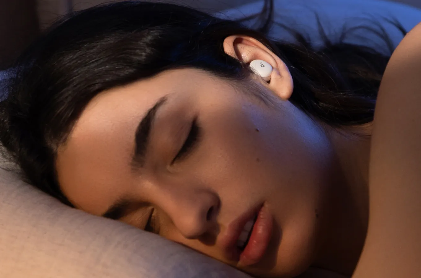 Woman wearing Soundcore Sleep A30 earbuds while sleeping.